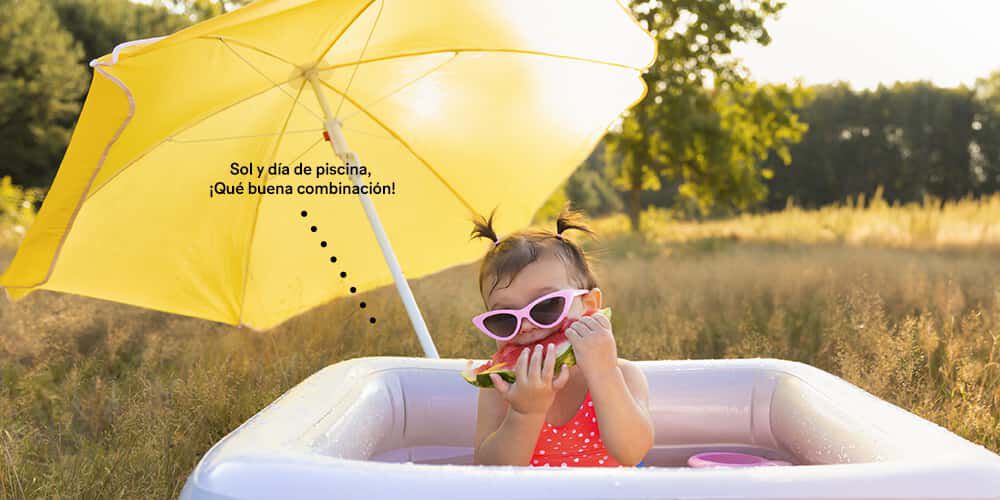 Bebé en piscina inflable comiendo patilla.